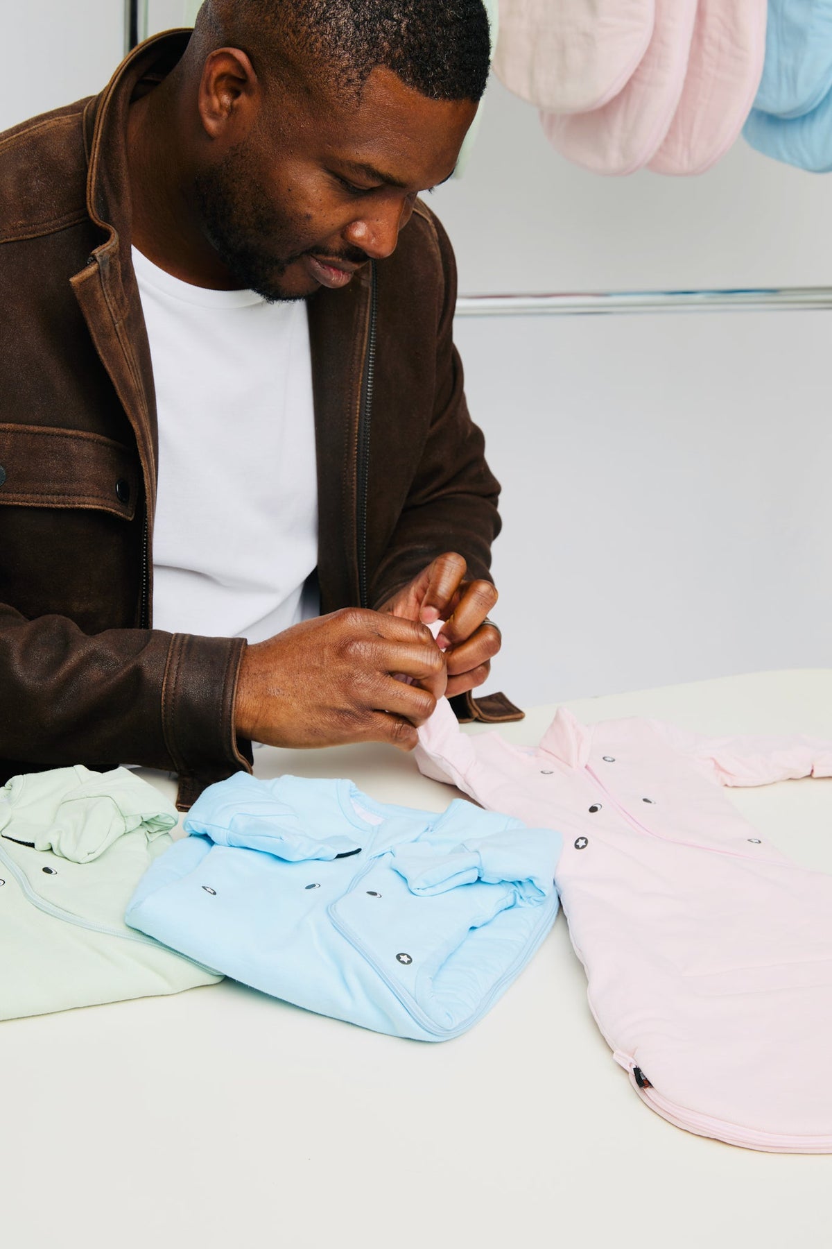Oge, founder of Nolele, closing the magnets on a Light Pink Swaddle Easy at a table