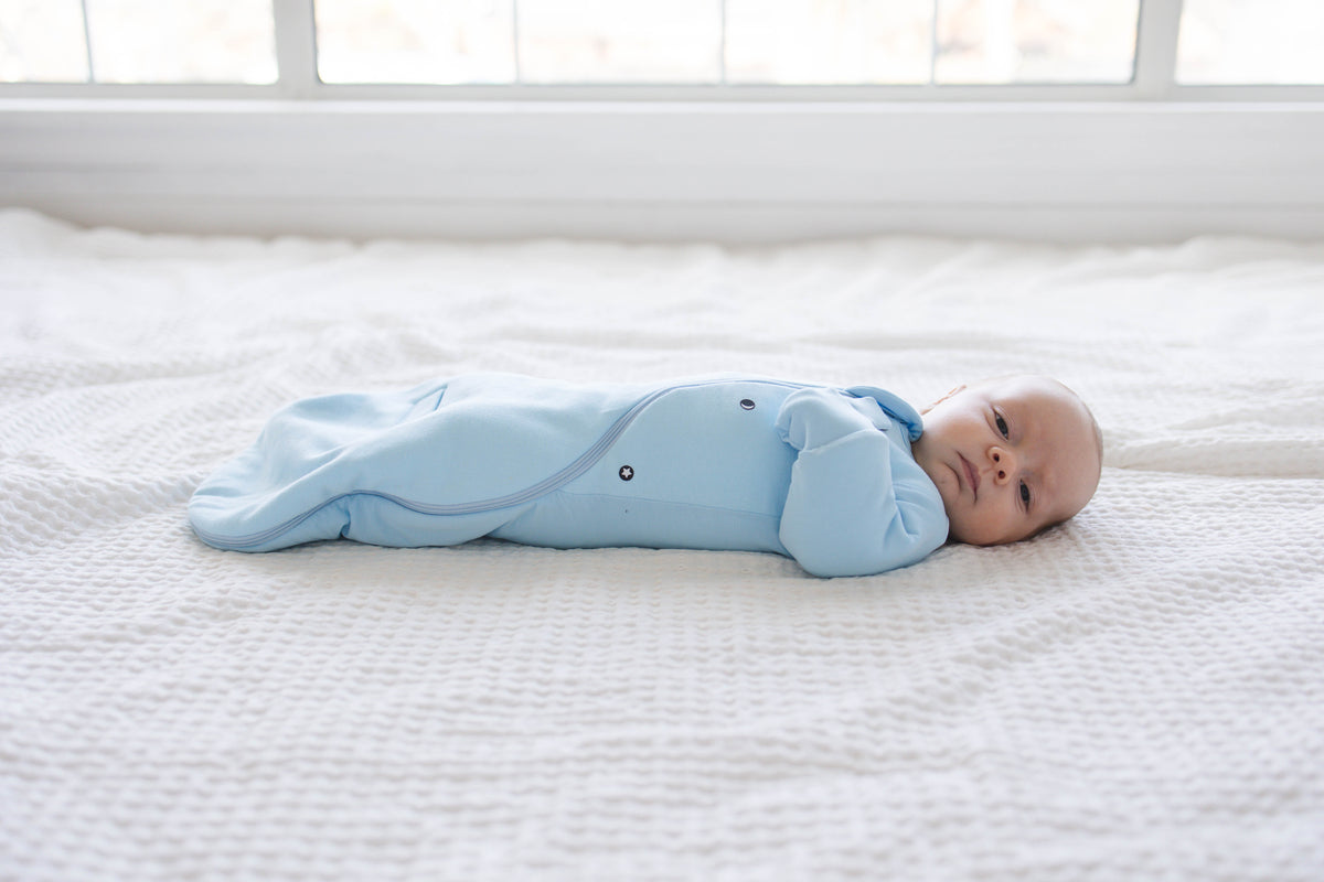 Baby on their back in a Sky Blue Swaddle Easy with both mittens folded over and closed
