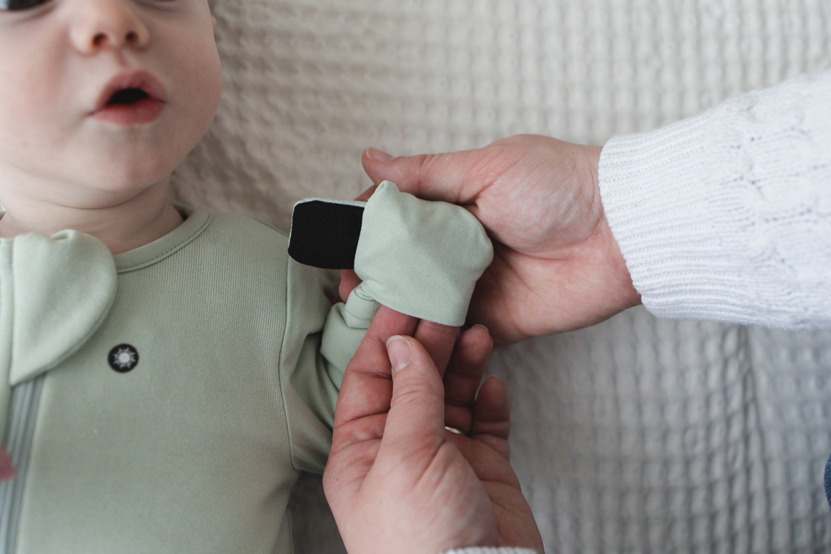 A parent folds a Sage Green mitten over so the magnet clicks shut